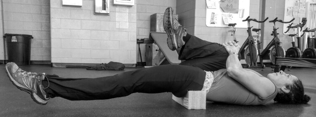 Person balancing horizontally on a wooden block indoors.