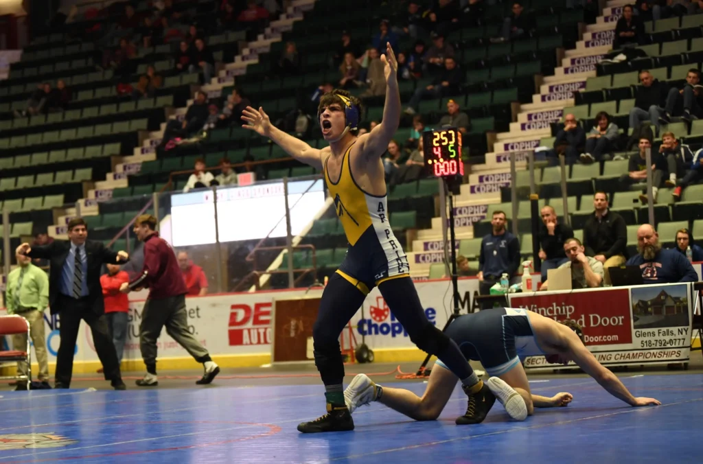 Wrestler celebrates victory over opponent in a match.